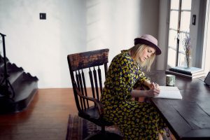A woman writing at a wooden desk